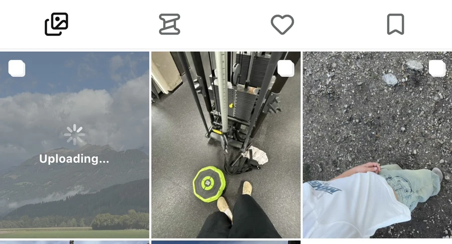 Profile photo grid with the new mountain post showing a spinner and Uploading label.